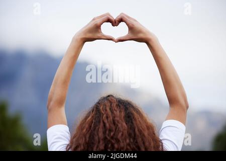 Raise your level of love. Rearview shot of an unrecognizable young woman out for an early morning hike in the mountains. Stock Photo