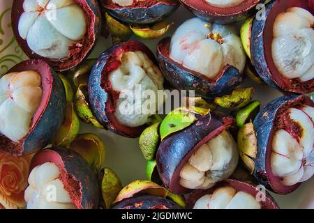 Closeup of tropical mangosteen fruits and cross section of purple skin and white seeds Stock Photo