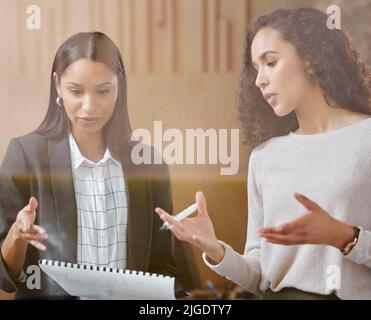 Your ideas are brilliant. two businesswomen working together while using a digital tablet. Stock Photo