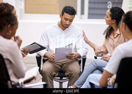 Were in this together. a group of businesspeople having a casual meeting in a boardroom and showing support to their coworker. Stock Photo