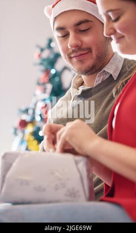 Love is a gift you get to open again and again. a happy young couple opening presents during Christmas at home. Stock Photo