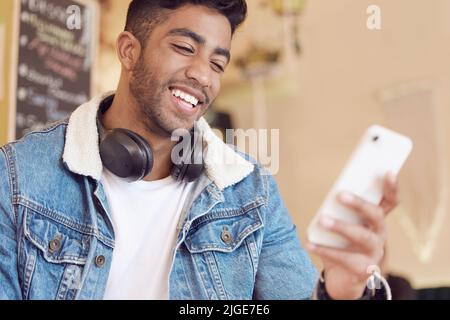 You make me smile. a young man using his smartphone to send a text message. Stock Photo
