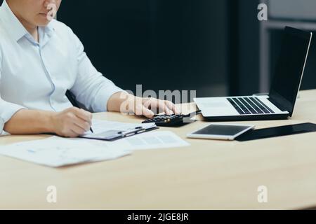 A close-up photo of a businessman's hand working on paperwork, an accountant, a financier, calculates financial statements and sums them up on a calculator Stock Photo