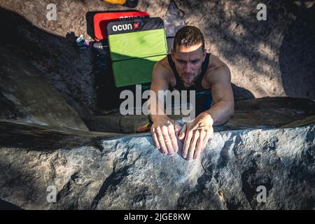 Climber jumps to top hold of dynamic jump boulder. Stock Photo