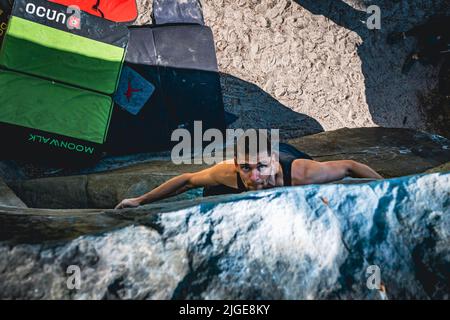 Climber jumps to top hold of dynamic jump boulder. Stock Photo