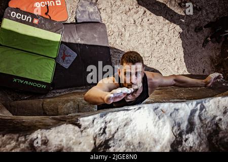 Climber jumps to top hold of dynamic jump boulder. Stock Photo