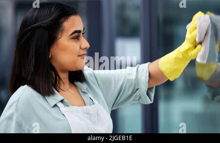 Cleaner windows for a better view. Closeup shot of a woman wearing gloves and using a cloth while cleaning windows. Stock Photo