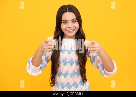 Child with positive expression, joyful and exciting over yellow background with empty space. Happy teenager girl rejoices success. Amazed expression Stock Photo