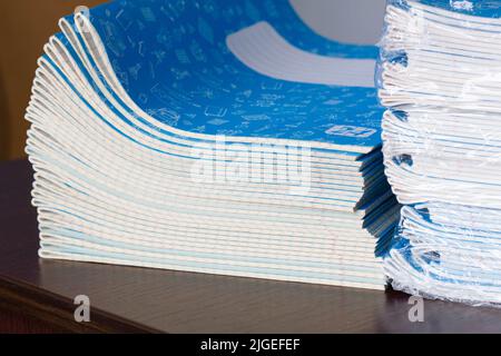 Stack of Notebooks. Back to school. A pack of blue school notebooks on the table in a classroom. Stack of exercise books. Packing checkered math Stock Photo