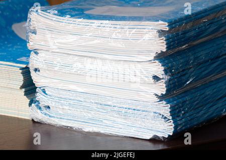 Stack of Notebooks. Back to school. A pack of blue school notebooks on the table in a classroom. Stack of exercise books. Packing checkered math Stock Photo