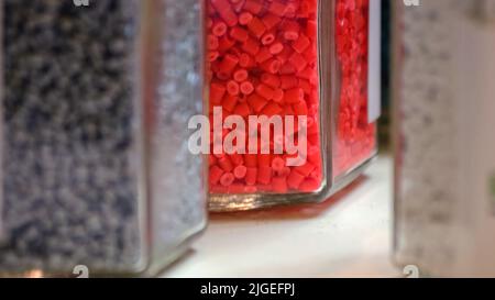 Transparent glass containers filled with colored cylinders. Glassware with assorted gum candies. Stock Photo