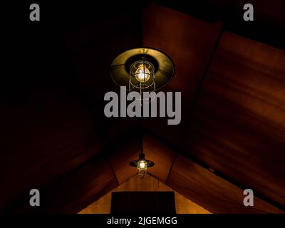 Old retro style lamp hanging on the ceiling inside the large glamping tent at a night. Lighting in the tent. Stock Photo