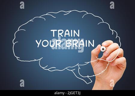Hand writing Train Your Brain on drawn human brain with white marker on transparent glass board. Stock Photo