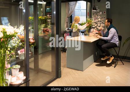 a man waiting for his bouquet being prepared by a florist in a flower shop Stock Photo