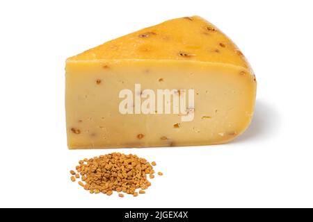 Piece of Gouda cheese with  Fenugreek and a heap of seeds in front  isolated on white background close up Stock Photo