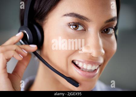 Im always ready to help. an attractive young call centre agent wearing a headset in the office during the day. Stock Photo