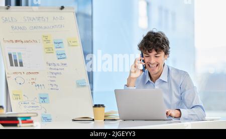This is shaping up to look amazing. a young businessman making a phone call on his smartphone while working on a laptop. Stock Photo