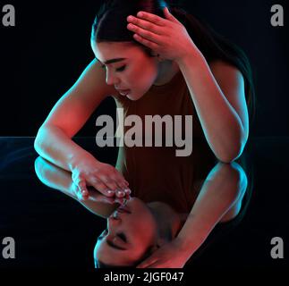 Sometimes its all about lighting. an attractive young female ballerina practicing in a dark dance studio. Stock Photo