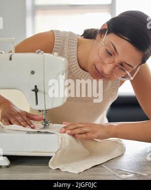 Sewing is her craft. a young woman using a sewing machine in her workshop. Stock Photo
