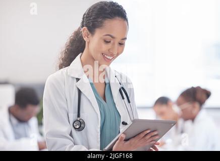Time to provide some positive feedback. a young female doctor using a digital tablet during a meeting. Stock Photo
