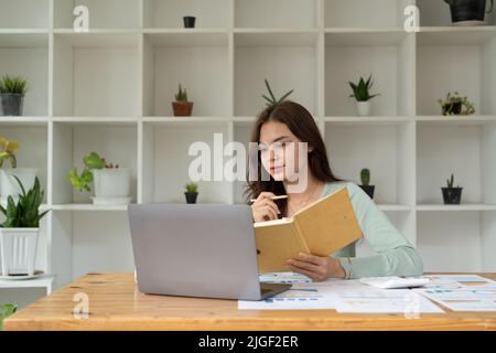 Concentrated female student busy studying using laptop make notes in notebook, focused man worker employee write watching webinar or online training Stock Photo