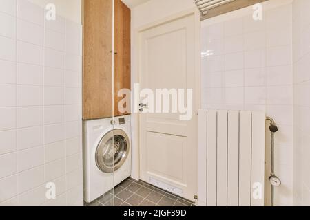 Modern home interior design of light bathroom with white ceramic tiles and washing machine with radiator Stock Photo