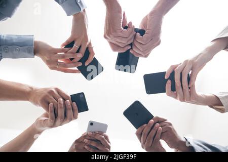 There is more power in unity than division. a group of businesspeople using their phones in synchronicity. Stock Photo