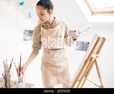 Paint from the heart. an attractive young woman painting on a canvas in her studio. Stock Photo