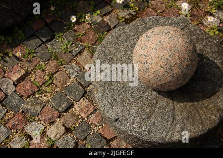 Decorative granite ball and round base on a pavement. Stock Photo