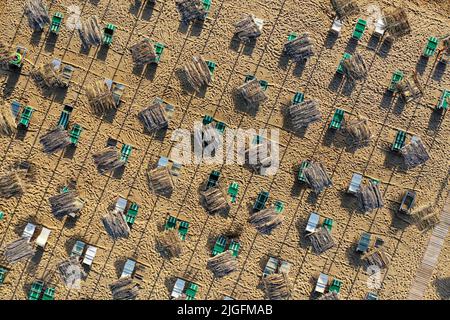 Aerial View of sunshades and beds during a summer morning on the beach of Vieste, Puglia, Italy. Stock Photo