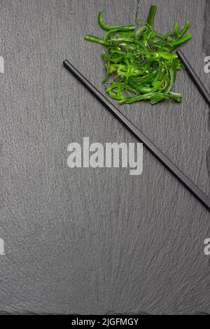 Seaweed with black sesame seeds and chopsticks on a stone board.  Copy space. Flat lay. Stock Photo