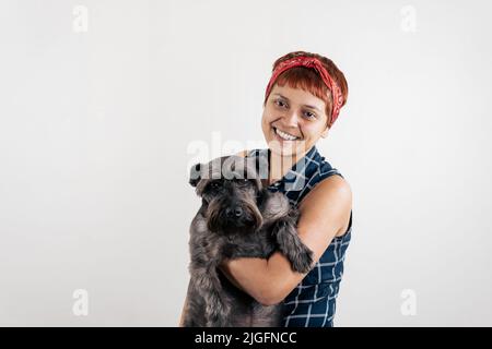 a mid age Latin woman carrying a dog Stock Photo