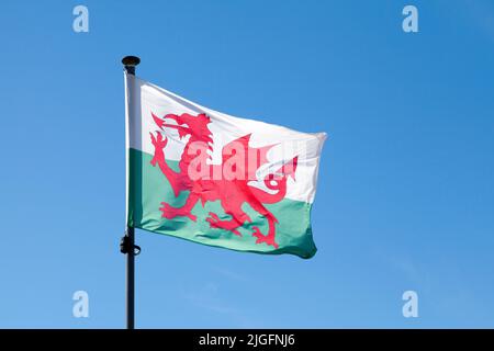 Flag of Wales waving atop of its pole against a blue sky. Stock Photo