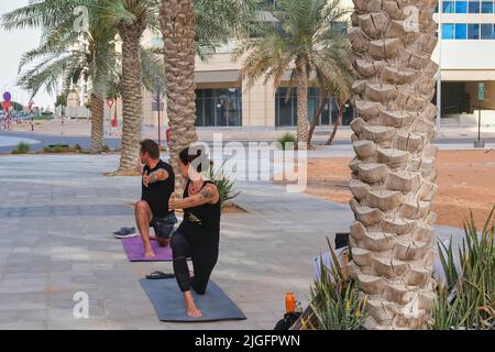 Couple doing yoga exercises in city street. Mature sporty woman and man practice yoga action exercise together outdoors Stock Photo