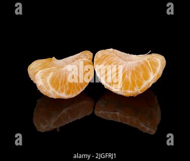 slices of ripe tangerines on a black background with reflection Stock Photo
