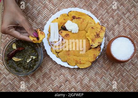 Person eating on table Indian popular dish makki di roti and Sarson da saag, mustard leaves curry and unleavened maize flour bread served in an authen Stock Photo
