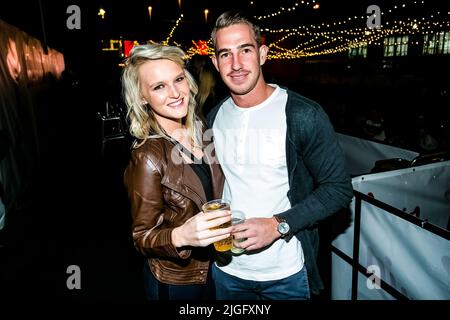 A happy young couple having drinks and posing at an outdoor party event Stock Photo