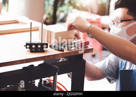 A carpenter measures the planks to assemble the parts, and build a wooden table for the customer Stock Photo