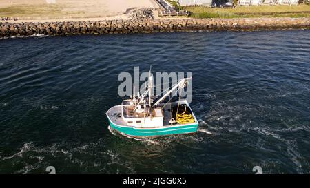 Aerial view of boat along the Manasquan Inlet heading to the Atlantic Ocean In Manasquan, NJ Stock Photo