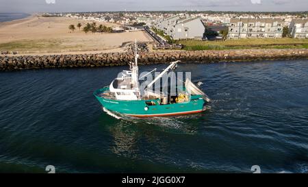 Aerial view of boat along the Manasquan Inlet heading to the Atlantic Ocean In Manasquan, NJ Stock Photo