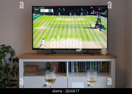 Cameron Norrie serves against Novak Djokovic in the first set at Wimbledon 2022 men's tennis semi final on 8th July 2022 on a tv in a lounge. UK Stock Photo