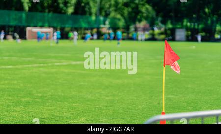 Corner flag on soccer field. Blurred silhouettes of soccer players. Football soccer field with green grass Stock Photo