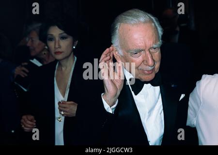 Legendary television news anchor Walter Cronkite, right, ties to hear as he walks to his table with news anchor Connie Chung, left, during the American News Women’s Club annual Roast and Toast Dinner at the Four Seasons Hotel, May 13, 1997 in Washington, D.C. Cronkite was presented with the Excellence in Journalism Award during the event. Stock Photo