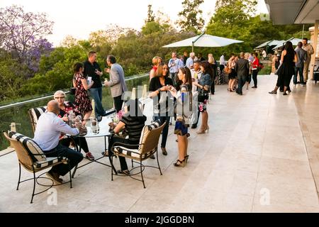Diverse people socializing at an outdoor cocktail party in Johannesburg, South Africa Stock Photo