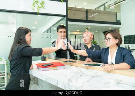 Business colleagues giving each other high five in the office. Symbol of unity and team spirit. Stock Photo