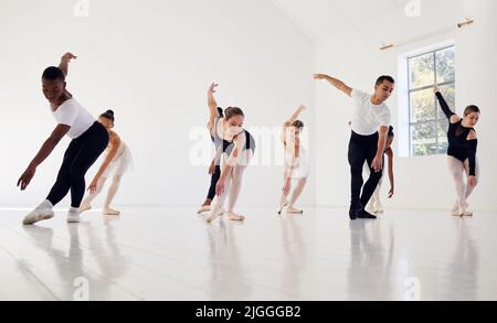 To dance is to be out of yourself. a group of ballet dancers practicing a routine in a dance studio. Stock Photo
