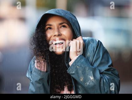 This weather sure is something. a young woman admiring the rain in the city. Stock Photo