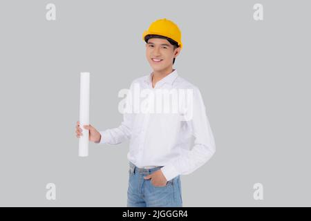 Portrait young asian man is engineer wearing helmet standing and holding blueprint with confident isolated on white background, handsome male is archi Stock Photo
