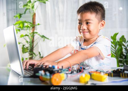 Asian kid boy learns coding and programming with laptop for Arduino robot car, Little child students typing code in computer with car toy, STEAM educa Stock Photo