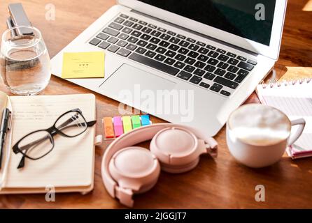 My workstation is my favourite space. an empty office with a laptop and set of headphones on the desk. Stock Photo